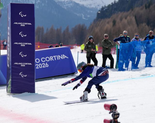 (260313) -- CORTINA D'AMPEZZO, March 13, 2026 (Xinhua) -- Kate Delson of the United States competes during the Para Snowboard Women's Banked Slalom SB-LL2 event at the Milan-Cortina 2026 Paralympic Winter Games in Cortina D'ampezzo, Italy, March 13, 2026. (Xinhua/Mu Yu)