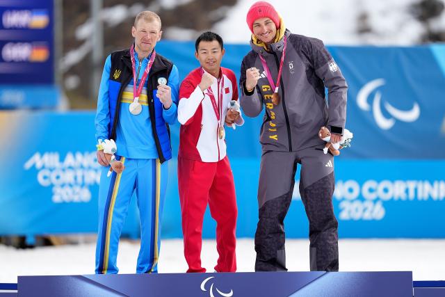 (260314) -- TESERO, March 14, 2026 (Xinhua) -- Gold medalist Jiayun Cai (C) of China poses with silver medalist Grygorii Vovchynskyi (L) of Ukraine and bronze medalist Marco Maier of Germany after the para biathlon men's sprint pursuit standing at the Milan-Cortina 2026 Paralympic Winter Games in Tesero, Italy, March 13, 2026. (Xinhua/Hou Zhaokang)