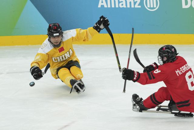 (260314) -- MILAN, March 14, 2026 (Xinhua) -- Wang Jujiang (L) of China passes the ball during the Para Ice Hockey semifinal match between the Canada and China at the Milan-Cortina 2026 Paralympic Winter Games in Milan , Italy, March 13, 2025. (Xinhua/Hou Jun)