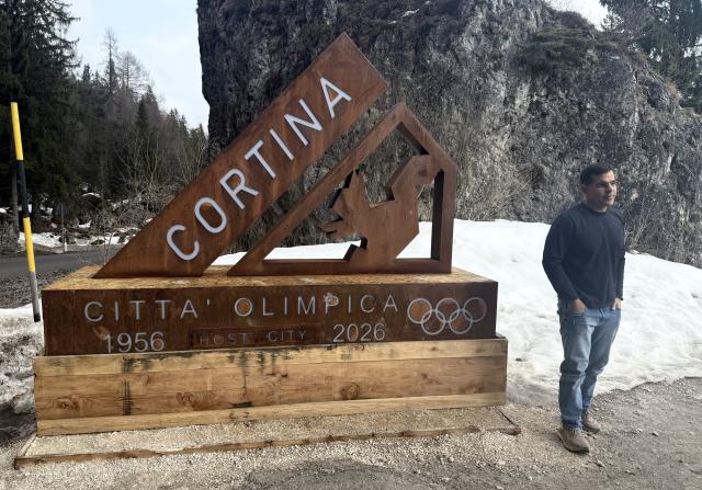 (260314) -- CORTINA D'AMPEZZO, March 14, 2026 (Xinhua) -- A tourist takes a photo with a sign in Cortina d'Ampezzo, Italy, on March 3, 2026. Cortina d'Ampezzo, nestled in the Dolomites, a UNESCO World Heritage Site, is a winter sports destination that has hosted the Winter Olympics twice. The 1956 Winter Olympic Games left enduring venues such as the Cortina Curling Stadium, which hosted the curling events at the 2026 Winter Olympic Games and is hosting the wheelchair curling at the Paralympic Winter Games.  
Cortina's winter sports heritage dates back to 1897, with legendary slopes including the Olympia delle Tofane.
As the 2026 Paralympic Winter Games conclude on March 15, Cortina will host the closing ceremony. The flame's extinguishment here will symbolize unity, bridging 70 years of Olympic legacy. (Xinhua/Cai Yang)