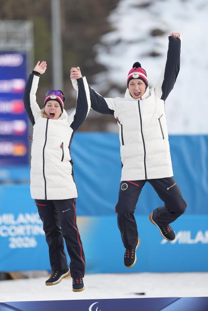 (260314) -- TESERO, March 14, 2026 (Xinhua) -- Gold medalists Carina Edlingerova (L) and guide Alexandr Patava of the Czech Republic celebrate on the podium during the awarding ceremony for the para biathlon women's sprint pursuit Vision Impaired at the Milan-Cortina 2026 Paralympic Winter Games in Tesero, Italy, March 13, 2026. (Xinhua/Hou Zhaokang)