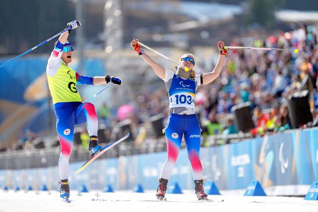 (260314) -- TESERO, March 14, 2026 (Xinhua) -- Gold medalists Carina Edlingerova (R) and guide Alexandr Patava of the Czech Republic cross the finish line during the para biathlon women's sprint pursuit Vision Impaired at the Milan-Cortina 2026 Paralympic Winter Games in Tesero, Italy, March 13, 2026. (Xinhua/Hou Zhaokang)