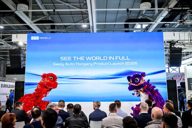 (260314) -- BUDAPEST, March 14, 2026 (Xinhua) -- People watch lion dance at a product launch event of Chinese car brand Geely during the International Automobile and Tuning Show in Budapest, Hungary, March 13, 2026. The International Automobile and Tuning Show kicked off on Friday, with the participation of several Chinese car brands. (Photo by David Balog/Xinhua)