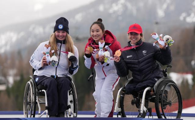 (260314) -- CORTINA D'AMPEZZO, March 14, 2026 (Xinhua) -- Gold medalist Zhang Wenjing (C) of China, silver medalist Nette Kiviranta (L) of Finland, bronze medalist Audrey Pascual Seco of Spain pose during the awarding ceremony for the para alpine skiing women's slalom sitting event at the Milan-Cortina 2026 Paralympic Winter Games in Cortina D'ampezzo, Italy, March 14, 2026. (Xinhua/Wang Kaiyan)