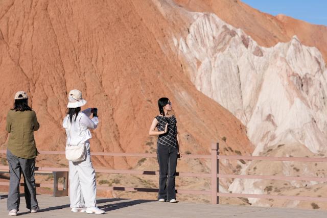 (260708) -- SUNAN, July 8, 2026 (Xinhua) -- Tourists visit a geopark in Sunan Yugur Autonomous County of Zhangye, northwest China's Gansu Province, July 7, 2026. The geopark covers an area of 17.34 square kilometers. The park features unique landforms with towering peaks, rugged mountains, jagged rock pillars, and vibrant colors. (Xinhua/Lang Bingbing)