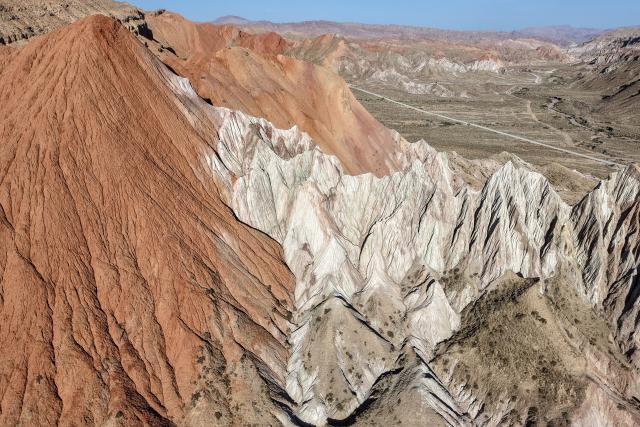 (260708) -- SUNAN, July 8, 2026 (Xinhua) -- An aerial drone photo taken on July 7, 2026 shows the view of a geopark in Sunan Yugur Autonomous County of Zhangye, northwest China's Gansu Province. The geopark covers an area of 17.34 square kilometers. The park features unique landforms with towering peaks, rugged mountains, jagged rock pillars, and vibrant colors. (Xinhua/Lang Bingbing)
