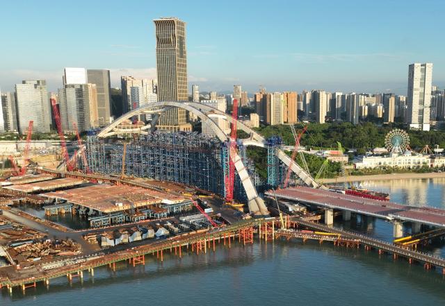 (260708) -- XIAMEN, July 8, 2026 (Xinhua) -- A drone photo taken on July 8, 2026 shows a view of the construction site of Guanyinshan Interchange, a project of the Xiamen section of the Xiamen-Kinmen bridge, in Xiamen, southeast China's Fujian Province. The two sides of an arch structure of Guanyinshan Interchange of the Xiamen section of the Xiamen-Kinmen bridge were joined together on Wednesday. (Xinhua/Lin Shanchuan)