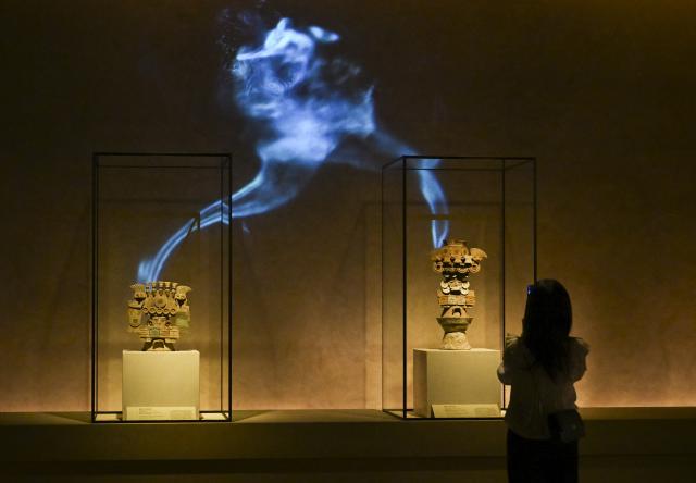 (260708) -- SHANGHAI, July 8, 2026 (Xinhua) -- A visitor takes photos of exhibits during the exhibition "On Top of the World Tree: Ancient Civilizations of the Americas" in Shanghai, east China, July 8, 2026. The exhibition showcases a total of 1,129 sets of precious artifacts from cultural institutions in Mexico, Peru and China. It will officially open to the public on July 9 and will run until Nov. 14, 2027. (Xinhua/Chen Haoming)