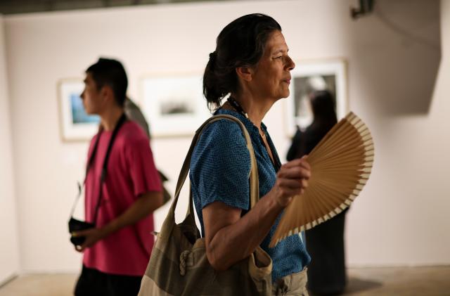(260708) -- ARLES, July 8, 2026 (Xinhua) -- A visitor fans herself while viewing exhibitions at the Rencontres d'Arles photography festival in Arles, France, July 8, 2026. France has experienced high temperatures this summer. (Xinhua/Wu Huiwo)