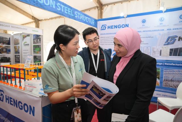 (260709) -- NAIROBI, July 9, 2026 (Xinhua) -- Lotus Yan (L), general manager of a Shandong-based company specializing in prefabricated steel buildings, introduces products to a visitor at the 27th Buildexpo Kenya in Nairobi, Kenya, July 8, 2026. Dozens of Chinese companies are showcasing their innovations at the 27th Buildexpo Kenya, which opened on Wednesday in the Kenyan capital, Nairobi.
   TO GO WITH "Chinese firms showcase innovations at Kenyan expo" (Xinhua/Yang Guang)