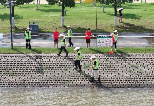 (260709) -- WUHAN, July 9, 2026 (Xinhua) -- A drone photo taken on July 8, 2026 shows flood control personnel and volunteers checking the condition of a levee along the Yangtze River in Wuchang District of Wuhan, central China's Hubei Province. Affected by heavy rainfall, the water level in Wuhan section of the Yangtze River rose obviously on Wednesday.
   The water level at the Yangtze Hankou monitoring station reached 25.11 meters, 0.11 meters above the warning mark. (Photo by Zhao Jun/Xinhua)