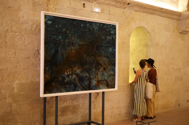 (260709) -- ARLES, July 9, 2026 (Xinhua) -- People stand beside an artwork displayed at the Rencontres d'Arles photography festival in Arles, France, July 8, 2026. The 57th Rencontres d'Arles photography festival lasts from July 6 to October 4. (Xinhua/Wu Huiwo)