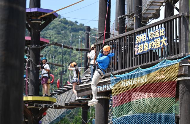 (260709) -- TIANJIN, July 9, 2026 (Xinhua) -- People experience amusement facilities at an amusement park in Xiaying Town of Jizhou District, north China's Tianjin, July 8, 2026. Xiaying Town in Jizhou District of Tianjin ushered in a travel boom as the summer vacation season began in China. In recent years, the town, taking advantages of its unique mountain, forest and water resources, has built a number of distinctive tourist attractions to meet people's various travelling demands. (Xinhua/Li Ran)