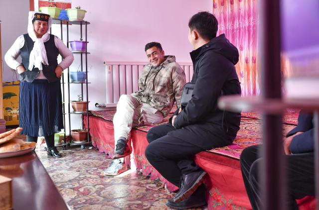 (260709) -- TAXKORGAN, July 9, 2026 (Xinhua) -- A local poverty alleviation official communicates with Nurkerim (C) to learn about the family's conditions one year after their relocation in Taxkorgan Tajik Autonomous County, northwest China's Xinjiang Uygur Autonomous Region, Nov. 25, 2019. This summer, happiness filled the air around the home of herdsman Duri Jarman. His youngest son Nurkerim tied the knot with his beloved woman. Weddings of the Tajik ethnic group usually last three days. Inscribed on the national intangible cultural heritage list in 2008, the wedding customs of the Tajik ethnic group maintain unique traditions and are always described as festivals of music, dance and food to showcase the resplendent newlyweds and their propitious marriage.
  In Aimin Village, this wedding also serves as a vivid epitome of the eight-year transformative leap brought by the poverty alleviation relocation program.
  In the winter of 2018, Jarman and his family benefited from the relocation policy for poverty alleviation and settled in Aimin Village. They gradually adapted to the changes, enjoying a new life different from that of their ancestors. Jarman ran a small grocery store with Nurkerim, while his eldest and second sons both landed stable new jobs. Nurkerim also bought a pickup truck to run a transport business. It was this business that brought him together with his wife. For this family, the relocation is not only an opportunity for development, but also a path leading to happiness.
  Over the past eight years, Jarman has expanded his courtyard and planted saplings year after year. His small yard, where not a single tree used to grow, is now shaded by lush, thriving woods. As relocation sites of the poverty alleviation relocation program, Aimin Village and neighboring Fumin Village are now home to 321 households, with at least one person employed per household on average. (Xinhua/Hu Huhu)