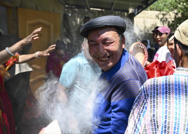 (260709) -- TAXKORGAN, July 9, 2026 (Xinhua) -- Relatives and friends of the bride sprinkle flour on the right shoulders of the members of the wedding procession as a blessing in Taxkorgan Tajik Autonomous County, northwest China's Xinjiang Uygur Autonomous Region, June 28, 2026. This summer, happiness filled the air around the home of herdsman Duri Jarman. His youngest son Nurkerim tied the knot with his beloved woman. Weddings of the Tajik ethnic group usually last three days. Inscribed on the national intangible cultural heritage list in 2008, the wedding customs of the Tajik ethnic group maintain unique traditions and are always described as festivals of music, dance and food to showcase the resplendent newlyweds and their propitious marriage.
  In Aimin Village, this wedding also serves as a vivid epitome of the eight-year transformative leap brought by the poverty alleviation relocation program.
  In the winter of 2018, Jarman and his family benefited from the relocation policy for poverty alleviation and settled in Aimin Village. They gradually adapted to the changes, enjoying a new life different from that of their ancestors. Jarman ran a small grocery store with Nurkerim, while his eldest and second sons both landed stable new jobs. Nurkerim also bought a pickup truck to run a transport business. It was this business that brought him together with his wife. For this family, the relocation is not only an opportunity for development, but also a path leading to happiness.
  Over the past eight years, Jarman has expanded his courtyard and planted saplings year after year. His small yard, where not a single tree used to grow, is now shaded by lush, thriving woods. As relocation sites of the poverty alleviation relocation program, Aimin Village and neighboring Fumin Village are now home to 321 households, with at least one person employed per household on average. (Xinhua/Hu Huhu)