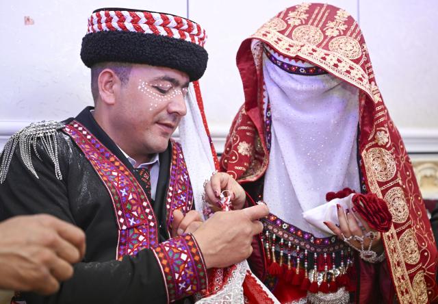 (260709) -- TAXKORGAN, July 9, 2026 (Xinhua) -- Nurkerim exchanges rings with his bride in Taxkorgan Tajik Autonomous County, northwest China's Xinjiang Uygur Autonomous Region, June 28, 2026. This summer, happiness filled the air around the home of herdsman Duri Jarman. His youngest son Nurkerim tied the knot with his beloved woman. Weddings of the Tajik ethnic group usually last three days. Inscribed on the national intangible cultural heritage list in 2008, the wedding customs of the Tajik ethnic group maintain unique traditions and are always described as festivals of music, dance and food to showcase the resplendent newlyweds and their propitious marriage.
  In Aimin Village, this wedding also serves as a vivid epitome of the eight-year transformative leap brought by the poverty alleviation relocation program.
  In the winter of 2018, Jarman and his family benefited from the relocation policy for poverty alleviation and settled in Aimin Village. They gradually adapted to the changes, enjoying a new life different from that of their ancestors. Jarman ran a small grocery store with Nurkerim, while his eldest and second sons both landed stable new jobs. Nurkerim also bought a pickup truck to run a transport business. It was this business that brought him together with his wife. For this family, the relocation is not only an opportunity for development, but also a path leading to happiness.
  Over the past eight years, Jarman has expanded his courtyard and planted saplings year after year. His small yard, where not a single tree used to grow, is now shaded by lush, thriving woods. As relocation sites of the poverty alleviation relocation program, Aimin Village and neighboring Fumin Village are now home to 321 households, with at least one person employed per household on average. (Xinhua/Hu Huhu)