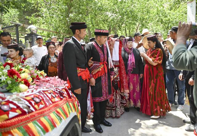 (260709) -- TAXKORGAN, July 9, 2026 (Xinhua) -- The newlyweds bid farewell to elders from the bride's family before the wedding procession sets off in Taxkorgan Tajik Autonomous County, northwest China's Xinjiang Uygur Autonomous Region, June 28, 2026. This summer, happiness filled the air around the home of herdsman Duri Jarman. His youngest son Nurkerim tied the knot with his beloved woman. Weddings of the Tajik ethnic group usually last three days. Inscribed on the national intangible cultural heritage list in 2008, the wedding customs of the Tajik ethnic group maintain unique traditions and are always described as festivals of music, dance and food to showcase the resplendent newlyweds and their propitious marriage.
  In Aimin Village, this wedding also serves as a vivid epitome of the eight-year transformative leap brought by the poverty alleviation relocation program.
  In the winter of 2018, Jarman and his family benefited from the relocation policy for poverty alleviation and settled in Aimin Village. They gradually adapted to the changes, enjoying a new life different from that of their ancestors. Jarman ran a small grocery store with Nurkerim, while his eldest and second sons both landed stable new jobs. Nurkerim also bought a pickup truck to run a transport business. It was this business that brought him together with his wife. For this family, the relocation is not only an opportunity for development, but also a path leading to happiness.
  Over the past eight years, Jarman has expanded his courtyard and planted saplings year after year. His small yard, where not a single tree used to grow, is now shaded by lush, thriving woods. As relocation sites of the poverty alleviation relocation program, Aimin Village and neighboring Fumin Village are now home to 321 households, with at least one person employed per household on average. (Xinhua/Hu Huhu)