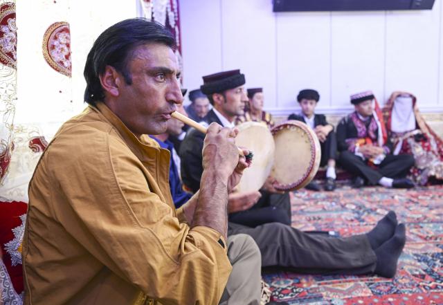 (260709) -- TAXKORGAN, July 9, 2026 (Xinhua) -- Members of the wedding procession play musical instruments at the bride's home in Taxkorgan Tajik Autonomous County, northwest China's Xinjiang Uygur Autonomous Region, June 28, 2026. This summer, happiness filled the air around the home of herdsman Duri Jarman. His youngest son Nurkerim tied the knot with his beloved woman. Weddings of the Tajik ethnic group usually last three days. Inscribed on the national intangible cultural heritage list in 2008, the wedding customs of the Tajik ethnic group maintain unique traditions and are always described as festivals of music, dance and food to showcase the resplendent newlyweds and their propitious marriage.
  In Aimin Village, this wedding also serves as a vivid epitome of the eight-year transformative leap brought by the poverty alleviation relocation program.
  In the winter of 2018, Jarman and his family benefited from the relocation policy for poverty alleviation and settled in Aimin Village. They gradually adapted to the changes, enjoying a new life different from that of their ancestors. Jarman ran a small grocery store with Nurkerim, while his eldest and second sons both landed stable new jobs. Nurkerim also bought a pickup truck to run a transport business. It was this business that brought him together with his wife. For this family, the relocation is not only an opportunity for development, but also a path leading to happiness.
  Over the past eight years, Jarman has expanded his courtyard and planted saplings year after year. His small yard, where not a single tree used to grow, is now shaded by lush, thriving woods. As relocation sites of the poverty alleviation relocation program, Aimin Village and neighboring Fumin Village are now home to 321 households, with at least one person employed per household on average. (Xinhua/Hu Huhu)