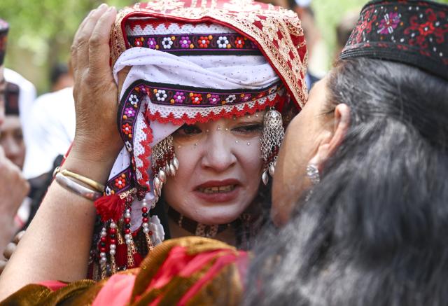 (260709) -- TAXKORGAN, July 9, 2026 (Xinhua) -- An elder kisses on the bride's cheek and whispers blessings in Taxkorgan Tajik Autonomous County, northwest China's Xinjiang Uygur Autonomous Region, June 28, 2026. This summer, happiness filled the air around the home of herdsman Duri Jarman. His youngest son Nurkerim tied the knot with his beloved woman. Weddings of the Tajik ethnic group usually last three days. Inscribed on the national intangible cultural heritage list in 2008, the wedding customs of the Tajik ethnic group maintain unique traditions and are always described as festivals of music, dance and food to showcase the resplendent newlyweds and their propitious marriage.
  In Aimin Village, this wedding also serves as a vivid epitome of the eight-year transformative leap brought by the poverty alleviation relocation program.
  In the winter of 2018, Jarman and his family benefited from the relocation policy for poverty alleviation and settled in Aimin Village. They gradually adapted to the changes, enjoying a new life different from that of their ancestors. Jarman ran a small grocery store with Nurkerim, while his eldest and second sons both landed stable new jobs. Nurkerim also bought a pickup truck to run a transport business. It was this business that brought him together with his wife. For this family, the relocation is not only an opportunity for development, but also a path leading to happiness.
  Over the past eight years, Jarman has expanded his courtyard and planted saplings year after year. His small yard, where not a single tree used to grow, is now shaded by lush, thriving woods. As relocation sites of the poverty alleviation relocation program, Aimin Village and neighboring Fumin Village are now home to 321 households, with at least one person employed per household on average. (Xinhua/Hu Huhu)