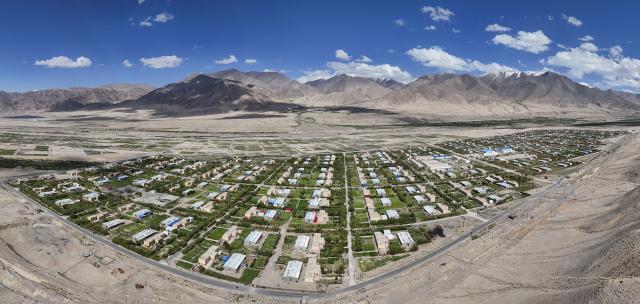 (260709) -- TAXKORGAN, July 9, 2026 (Xinhua) -- An aerial panoramic photo taken on June 30, 2026 shows a view of the Aimin Village and Fumin Village of Taxkorgan Tajik Autonomous County, northwest China's Xinjiang Uygur Autonomous Region. This summer, happiness filled the air around the home of herdsman Duri Jarman. His youngest son Nurkerim tied the knot with his beloved woman. Weddings of the Tajik ethnic group usually last three days. Inscribed on the national intangible cultural heritage list in 2008, the wedding customs of the Tajik ethnic group maintain unique traditions and are always described as festivals of music, dance and food to showcase the resplendent newlyweds and their propitious marriage.
  In Aimin Village, this wedding also serves as a vivid epitome of the eight-year transformative leap brought by the poverty alleviation relocation program.
  In the winter of 2018, Jarman and his family benefited from the relocation policy for poverty alleviation and settled in Aimin Village. They gradually adapted to the changes, enjoying a new life different from that of their ancestors. Jarman ran a small grocery store with Nurkerim, while his eldest and second sons both landed stable new jobs. Nurkerim also bought a pickup truck to run a transport business. It was this business that brought him together with his wife. For this family, the relocation is not only an opportunity for development, but also a path leading to happiness.
  Over the past eight years, Jarman has expanded his courtyard and planted saplings year after year. His small yard, where not a single tree used to grow, is now shaded by lush, thriving woods. As relocation sites of the poverty alleviation relocation program, Aimin Village and neighboring Fumin Village are now home to 321 households, with at least one person employed per household on average. (Xinhua/Hu Huhu)