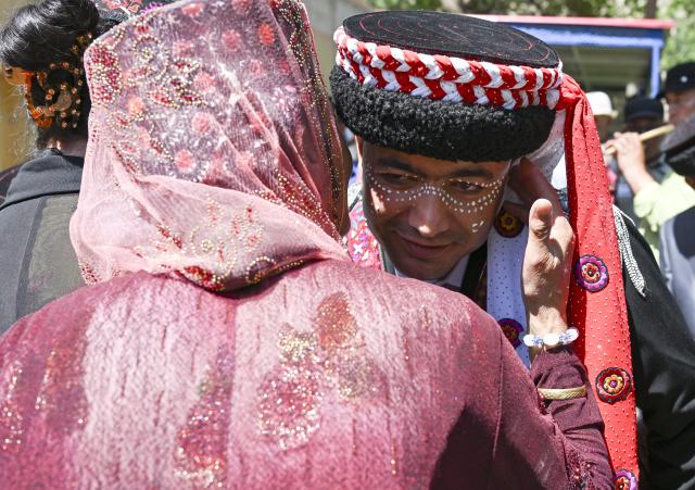 (260709) -- TAXKORGAN, July 9, 2026 (Xinhua) -- Nurkerim arrives at his bride's home and greets her elders in Taxkorgan Tajik Autonomous County, northwest China's Xinjiang Uygur Autonomous Region, June 28, 2026. This summer, happiness filled the air around the home of herdsman Duri Jarman. His youngest son Nurkerim tied the knot with his beloved woman. Weddings of the Tajik ethnic group usually last three days. Inscribed on the national intangible cultural heritage list in 2008, the wedding customs of the Tajik ethnic group maintain unique traditions and are always described as festivals of music, dance and food to showcase the resplendent newlyweds and their propitious marriage.
  In Aimin Village, this wedding also serves as a vivid epitome of the eight-year transformative leap brought by the poverty alleviation relocation program.
  In the winter of 2018, Jarman and his family benefited from the relocation policy for poverty alleviation and settled in Aimin Village. They gradually adapted to the changes, enjoying a new life different from that of their ancestors. Jarman ran a small grocery store with Nurkerim, while his eldest and second sons both landed stable new jobs. Nurkerim also bought a pickup truck to run a transport business. It was this business that brought him together with his wife. For this family, the relocation is not only an opportunity for development, but also a path leading to happiness.
  Over the past eight years, Jarman has expanded his courtyard and planted saplings year after year. His small yard, where not a single tree used to grow, is now shaded by lush, thriving woods. As relocation sites of the poverty alleviation relocation program, Aimin Village and neighboring Fumin Village are now home to 321 households, with at least one person employed per household on average. (Xinhua/Hu Huhu)