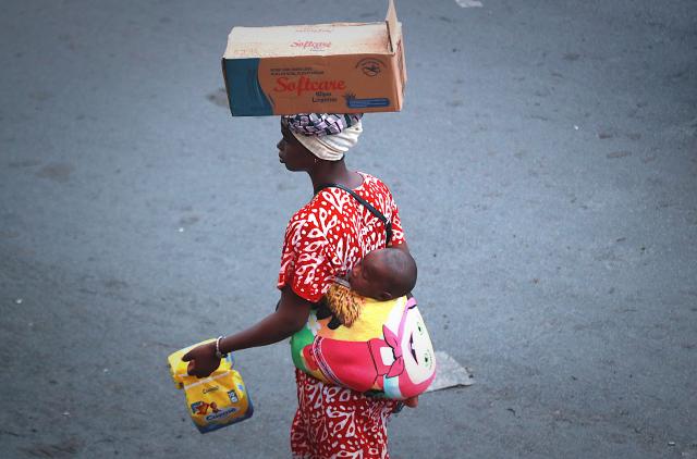 (260710) -- ABIDJAN, July 10, 2026 (Xinhua) -- A woman carries her child on her back while selling goods on a street in Abidjan, Cote d'Ivoire, on July 9, 2026. (Photo by Yvan Sonh/Xinhua)