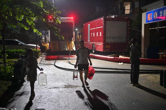 (260710) -- GUIGANG, July 10, 2026 (Xinhua) -- Residents fetching water pass by emergency water pumping and power supply vehicles dispatched from south China's Guangdong Province at a community in Guigang, south China's Guangxi Zhuang Autonomous Region, July 9, 2026.
  Guigang has suffered severe flooding due to torrential rains brought by Typhoon Maysak and upstream inflows. Local authorities have mobilized rescue forces to work around the clock, making every effort to ensure basic living needs for stranded residents. (Xinhua/Zhou Hua)