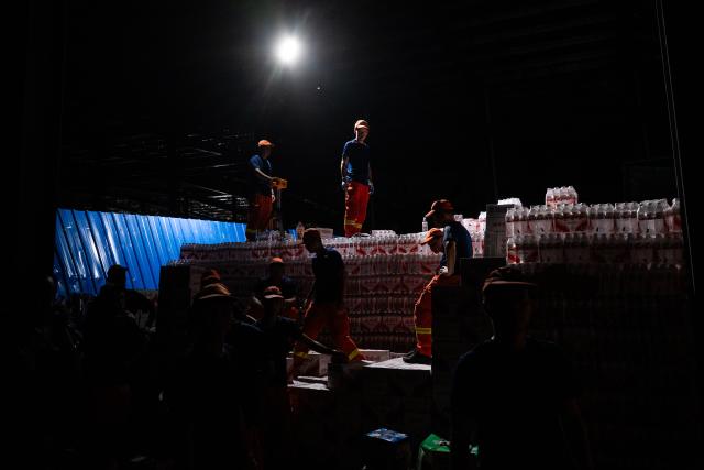 (260710) -- HUANGGANG, July 10, 2026 (Xinhua) -- Rescuers work at a tornado-affected logistics park in Huangzhou District of Huanggang, central China's Hubei Province, July 9, 2026. A large batch of essential supplies including rice, flour, grains, edible oil, and convenience foods had been put at risk of water damage inside a logistics park of Huanggang since a tornado hit the city on Monday. Rescuers worked around the clock and successfully relocated the supplies to designated storage sites after more than 10 hours of effort from Thursday afternoon to Friday morning. (Xinhua/Wu Zhizun)