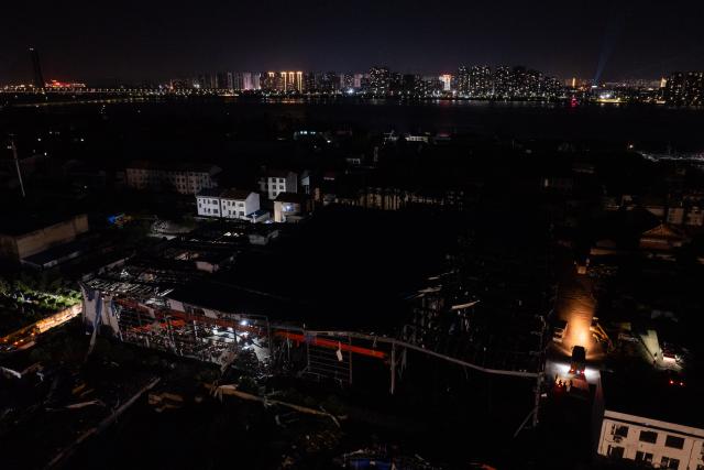 (260710) -- HUANGGANG, July 10, 2026 (Xinhua) -- An aerial drone photo taken on July 9, 2026 shows rescuers transfering supplies at a tornado-affected logistics park in Huangzhou District of Huanggang, central China's Hubei Province. A large batch of essential supplies including rice, flour, grains, edible oil, and convenience foods had been put at risk of water damage inside a logistics park of Huanggang since a tornado hit the city on Monday. Rescuers worked around the clock and successfully relocated the supplies to designated storage sites after more than 10 hours of effort from Thursday afternoon to Friday morning. (Xinhua/Wu Zhizun)