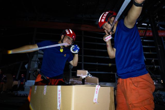(260710) -- HUANGGANG, July 10, 2026 (Xinhua) -- Rescuers transfer supplies at a tornado-affected logistics park in Huangzhou District of Huanggang, central China's Hubei Province, July 9, 2026. A large batch of essential supplies including rice, flour, grains, edible oil, and convenience foods had been put at risk of water damage inside a logistics park of Huanggang since a tornado hit the city on Monday. Rescuers worked around the clock and successfully relocated the supplies to designated storage sites after more than 10 hours of effort from Thursday afternoon to Friday morning. (Xinhua/Wu Zhizun)