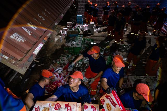 (260710) -- HUANGGANG, July 10, 2026 (Xinhua) -- Rescuers transfer supplies at a tornado-affected logistics park in Huangzhou District of Huanggang, central China's Hubei Province, July 9, 2026. A large batch of essential supplies including rice, flour, grains, edible oil, and convenience foods had been put at risk of water damage inside a logistics park of Huanggang since a tornado hit the city on Monday. Rescuers worked around the clock and successfully relocated the supplies to designated storage sites after more than 10 hours of effort from Thursday afternoon to Friday morning. (Xinhua/Wu Zhizun)