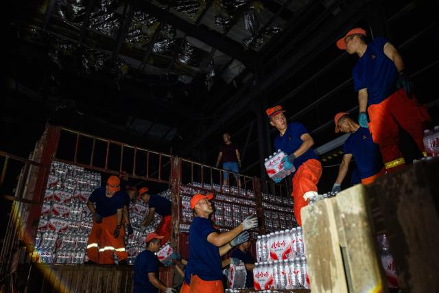 (260710) -- HUANGGANG, July 10, 2026 (Xinhua) -- Rescuers transfer supplies at a tornado-affected logistics park in Huangzhou District of Huanggang, central China's Hubei Province, July 9, 2026. A large batch of essential supplies including rice, flour, grains, edible oil, and convenience foods had been put at risk of water damage inside a logistics park of Huanggang since a tornado hit the city on Monday. Rescuers worked around the clock and successfully relocated the supplies to designated storage sites after more than 10 hours of effort from Thursday afternoon to Friday morning. (Xinhua/Wu Zhizun)