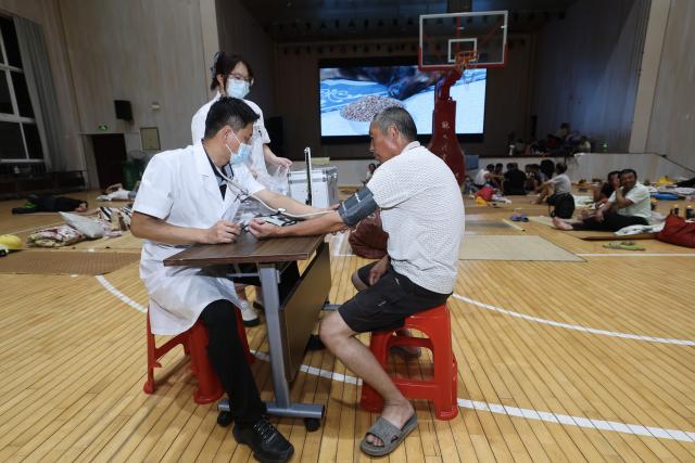 (260710) -- BEIJING, July 10, 2026 (Xinhua) -- Medical workers conduct treatment for people who take shelter at a middle school in Shitang Town of Wenling City, east China's Zhejiang Province, July 10, 2026. China's national observatory on Friday renewed an orange alert for Typhoon Bavi, the ninth typhoon of 2026, which is expected to bring gales and heavy rain to eastern China. Affected regions are on high alert, with all prevention and response measures fully implemented to safeguard people's lives and property. (Xinhua/Xu Yu)