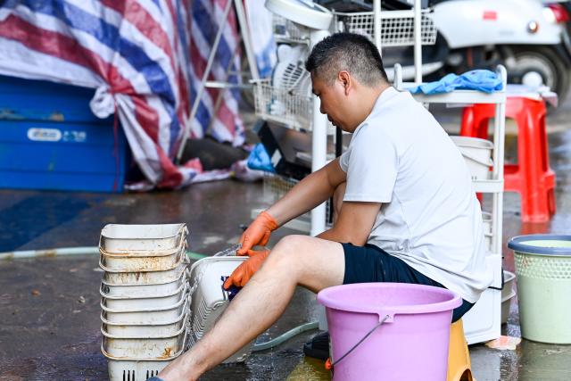 (260710) -- NANNING, July 10, 2026 (Xinhua) -- A vendor cleans his goods in Guigang, south China's Guangxi Zhuang Autonomous Region, July 10, 2026. The local authorities beef up restoration efforts after torrential rains caused by Typhoon Maysak. (Xinhua/Cao Yiming)