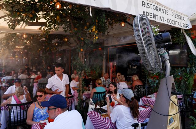 (260710) -- ROME, July 10, 2026 (Xinhua) -- Customers enjoy their food beside a misting fan at a restaurant in Rome, Italy, July 10, 2026. A new round of heatwave is underway around Italy, with the average temperature consistently around 35 degrees Celsius and peaks exceeding 40 degrees Celsius. (Xinhua/Wang Kaiyan)