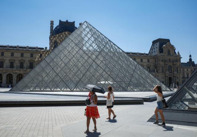(260710) -- PARIS, July 10, 2026 (Xinhua) -- Visitors holding umbrellas are seen near the Louvre Museum during the heatwave in Paris, France, July 10, 2026. The Louvre Museum announced on Thursday that it will close two hours earlier than usual from Friday through next Monday as France braces for another heatwave. (Xinhua/Wu Huiwo)