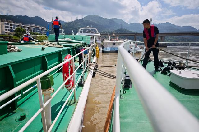 (260711) -- WENZHOU, July 11, 2026 (Xinhua) -- A police officer (R) inspects the reinforced mooring ropes on a vessel berthing along the Oujiang River in Wenzhou, east China's Zhejiang Province, July 10, 2026. Zhejiang Province in east China raised its typhoon emergency response to the highest level on Saturday as Typhoon Bavi, the 9th typhoon of 2026, barrels toward the country's eastern coast, triggering widespread disaster prevention efforts across multiple provincial-level regions. 
  According to Zhejiang Meteorological Observatory, the severe typhoon was located some 489 km off the coast of the province's city of Wenzhou as of 9 a.m. on Saturday, packing strong-typhoon-level winds near its center. It is forecast to move northwest at a speed of 30 to 35 km per hour and make landfall in Zhejiang around midnight. (Xinhua/Jiang Han)