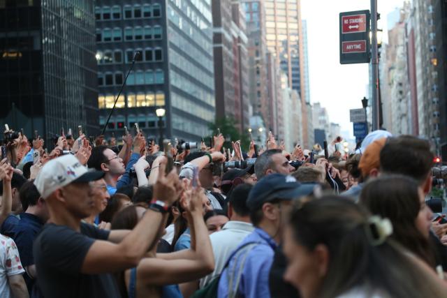 (260713) -- NEW YORK, July 13, 2026 (Xinhua) -- People take photos of the Manhattanhenge in Manhattan of New York, the United States, on July 12, 2026. The Manhattanhenge refers to the twice-a-year circumstance during which the setting sun aligns precisely with the east-west streets of Manhattan. (Xinhua/Zhang Fengguo)