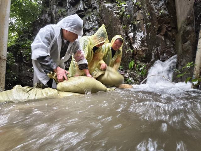 (260713) -- BEIJING, July 13, 2026 (Xinhua) -- This photo taken by a mobile phone shows party members and officials placing sandbags to hold back floodwaters at Gaoling Village of Lin'an District in Hangzhou, east China's Zhejiang Province, July 12, 2026.
  As extreme weather has battered multiple regions across China in recent days, local authorities have implemented disaster prevention and relief measures to safeguard people's lives and property. (Photo by Hu Jianhuan/Xinhua)