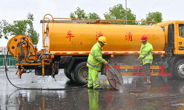 (260713) -- BEIJING, July 13, 2026 (Xinhua) -- Municipal workers clean a gutter inlet in Xianju County of Taizhou City, east China's Zhejiang Province, July 11, 2026.
  As extreme weather has battered multiple regions across China in recent days, local authorities have implemented disaster prevention and relief measures to safeguard people's lives and property. (Photo by Wang Huabin/Xinhua)