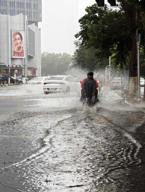 (260713) -- SHENYANG, July 13, 2026 (Xinhua) -- Citizens ride a motorcycle on a flooded road amid rain in Shenyang, northeast China's Liaoning Province, on July 13, 2026. From Sunday to Monday, heavy to torrential rain lashed central Liaoning Province. Several cities, including Shenyang and Fushun, suspended classes, business operations and work on Monday as a precaution, while water levels in several rivers rose significantly due to the heavy rainfall. (Xinhua/Li Gang)