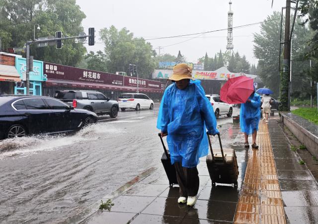 (260713) -- SHENYANG, July 13, 2026 (Xinhua) -- Citizens walk amid rain in Shenyang, northeast China's Liaoning Province, on July 13, 2026. From Sunday to Monday, heavy to torrential rain lashed central Liaoning Province. Several cities, including Shenyang and Fushun, suspended classes, business operations and work on Monday as a precaution, while water levels in several rivers rose significantly due to the heavy rainfall. (Xinhua/Li Gang)