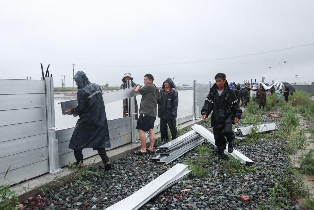 (260713) -- BEIJING, July 13, 2026 (Xinhua) -- Staff members install boards against flood on a flood control embankment in Dawa District of Panjin City, northeast China's Liaoning Province, July 13, 2026. As extreme weather has swept across multiple regions across China in recent days, local authorities have implemented disaster prevention and relief measures to safeguard people's lives and property. (Xinhua/Pan Yulong)