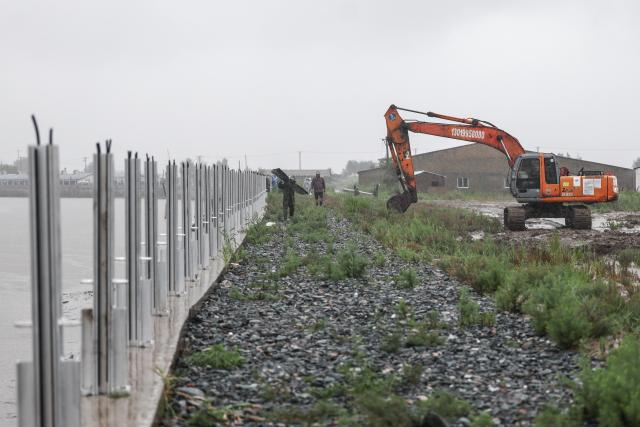 (260713) -- BEIJING, July 13, 2026 (Xinhua) -- Staff members install boards against flood on a flood control embankment in Dawa District of Panjin City, northeast China's Liaoning Province, July 13, 2026. As extreme weather has swept across multiple regions across China in recent days, local authorities have implemented disaster prevention and relief measures to safeguard people's lives and property. (Xinhua/Pan Yulong)