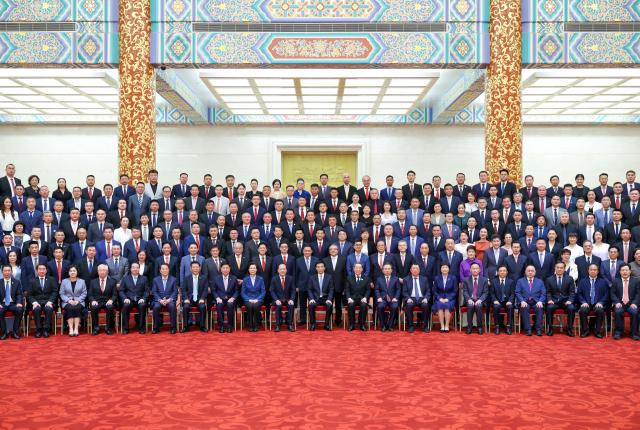(260713) -- BEIJING, July 13, 2026 (Xinhua) -- Wang Huning, a member of the Standing Committee of the Political Bureau of the Communist Party of China (CPC) Central Committee and chairman of the National Committee of the Chinese People's Political Consultative Conference, meets and poses for a group photo with representatives to the 11th Conference for Friendship of Overseas Chinese Associations in Beijing, capital of China, July 13, 2026. The conference opened here on Monday. (Xinhua/Liu Bin)