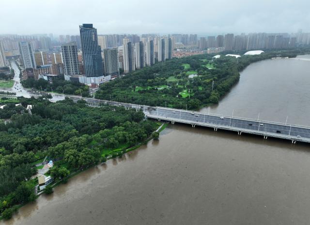 (260714) -- BEIJING, July 14, 2026 (Xinhua) -- An aerial drone photo taken on July 13, 2026 shows a section of the Hunhe River in Shenyang, northeast China's Liaoning Province. From Sunday to Monday, heavy to torrential rain lashed central Liaoning Province. Several cities, including Shenyang and Fushun, suspended classes, business operations and work on Monday as a precaution, while water levels in several rivers rose significantly due to the heavy rainfall. (Xinhua/Li Gang)