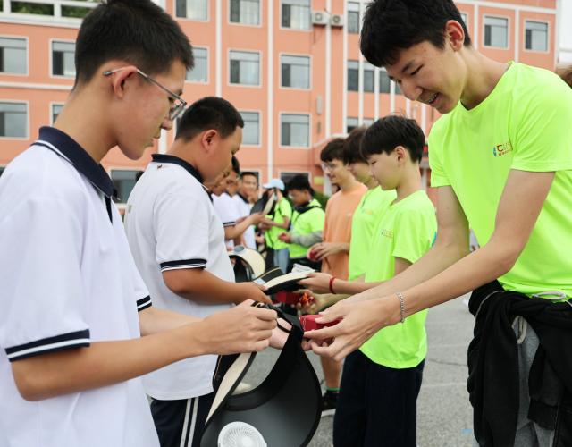 (260714) -- ANSHAN, July 14, 2026 (Xinhua) -- Members of a study tour exchange gifts with local students in Xiuyan Man Autonomous County, northeast China's Liaoning Province, July 12, 2026. Nearly 50 international teachers and students from five countries, including Mongolia, Greece, Thailand, Vietnam and Indonesia, joined the study tour, visiting modern agricultural production sites in northern China and enjoying immersive experiences of traditional Chinese culture. (Xinhua/Li Gang)