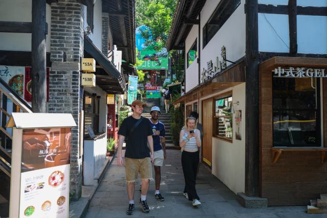 (260714) -- CHONGQING, July 14, 2026 (Xinhua) -- Foreign tourists visit Xiahaoli Ancient Street in Nan'an District of southwest China's Chongqing Municipality, July 10, 2026. Since the beginning of this year, inbound and outbound passenger traffic at Chongqing Jiangbei International Airport has continued to grow, with a significant increase in foreign passenger traffic. In the first half of 2026, the airport handled more than 1.48 million inbound and outbound passenger trips, up 39.5 percent year on year. (Xinhua/Huang Wei)