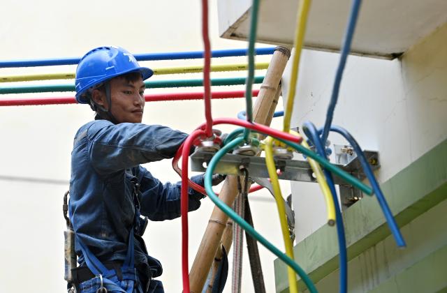 (260714) -- GUIGANG, July 14, 2026 (Xinhua) -- A staff member performs emergency repairing at a residential compound in Guigang City, south China's Guangxi Zhuang Autonomous Region, July 14, 2026. The power supplier in Guigang has mobilized all hands available to restore power supply as flooding inflicted by typhoon Maysak subsides in the city. (Xinhua/Lu Boan)