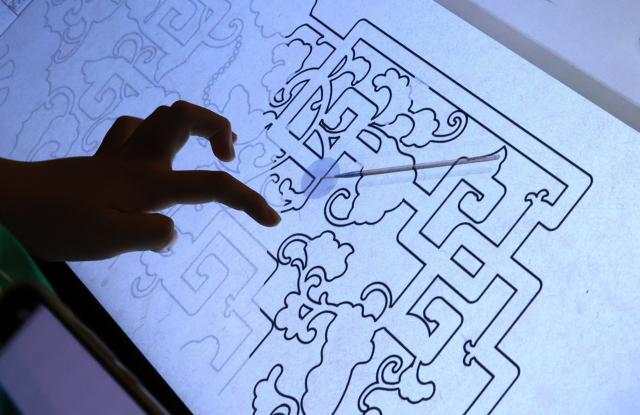 (260714) -- BEIJING, July 14, 2026 (Xinhua) -- A visitor tries a simulated handcraft experience during "A Garden Within: An Immersive Light and Shadow Exhibition of the Qianlong Garden" at National Museum of Classic Books in Beijing, capital of China, July 14, 2026. The exhibition, which features multiple immersive scenarios and interactive installations, is held here from July 9 to Dec. 6.
   The Qianlong Garden, also known as the Garden of the Palace of Tranquil Longevity, was built by Emperor Qianlong (1711-1799) of Qing Dynasty (1644-1911) as a private retreat for his later years in the Forbidden City, or today's Palace Museum. (Xinhua/Yin Gang)